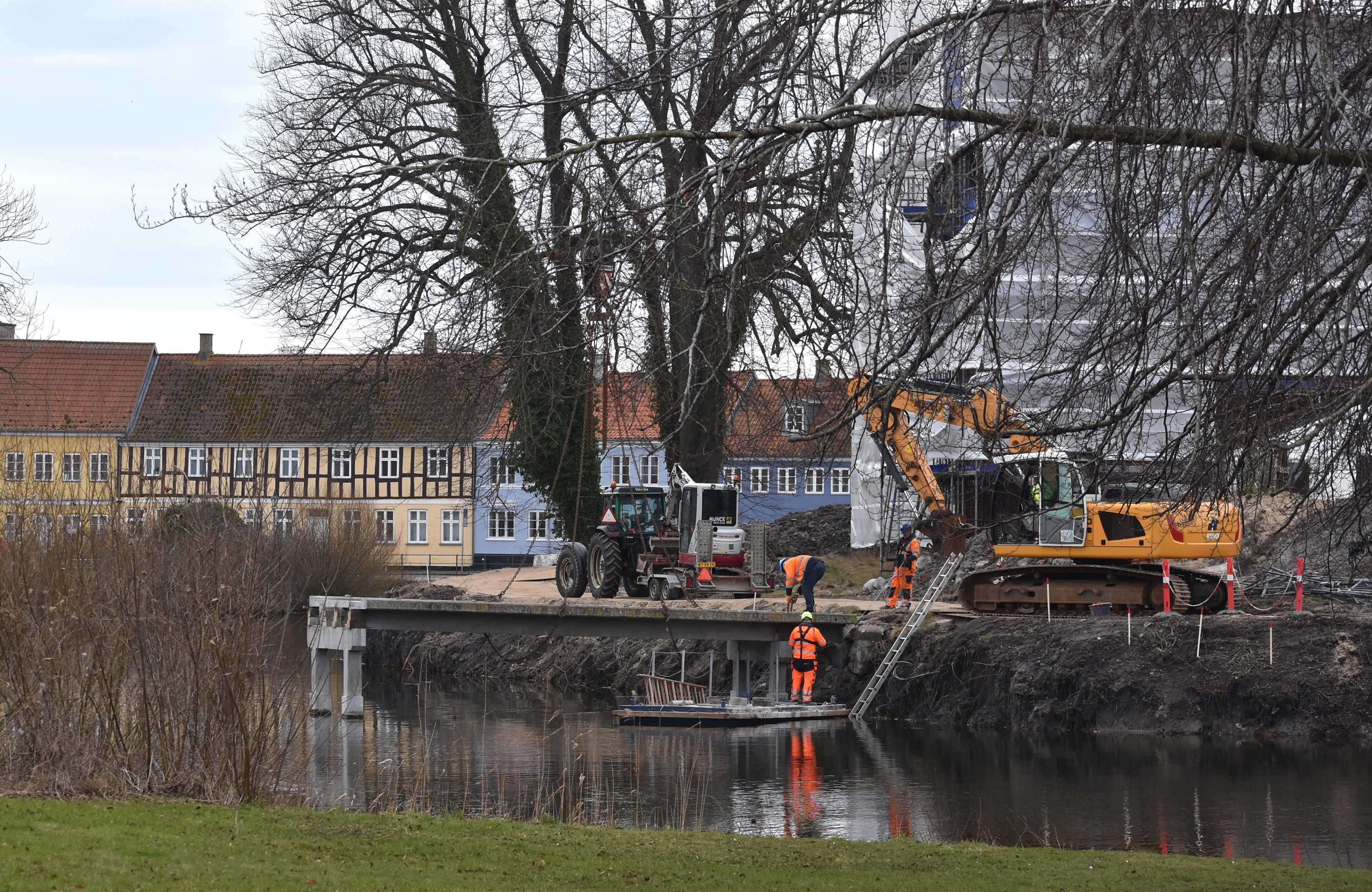 Arbejdsmænd på tømmerflåde i voldgraven der arbejder på at fjerne broen